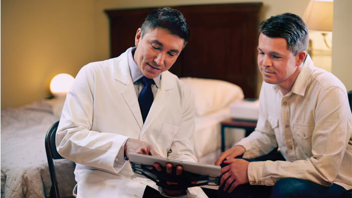 Bilde av lege som viser resultater til en mann p&aring; et nettbrett