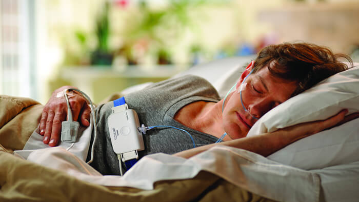 Bilde av mann som sover p&aring; siden i sengen og bruker en Philips-s&oslash;vntest