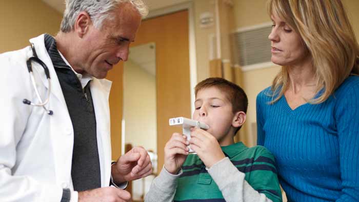 helsepersonell som hjelper et barn med et astmaprodukt