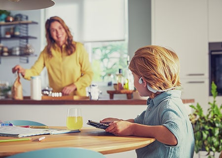 Gutt som ser på video mens han bruker trådløse Philips-barnehodetelefoner som sitter på øret