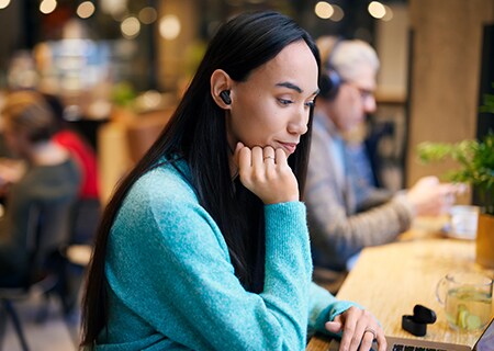 Kvinne som kler på en kaffebar med Philips T3508 støyreduserende trådløse hodetelefoner