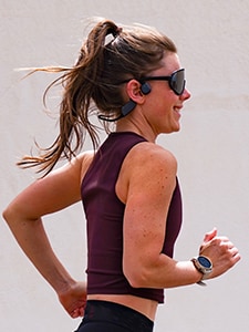 Kvinne som løper iført hodetelefoner med benledning