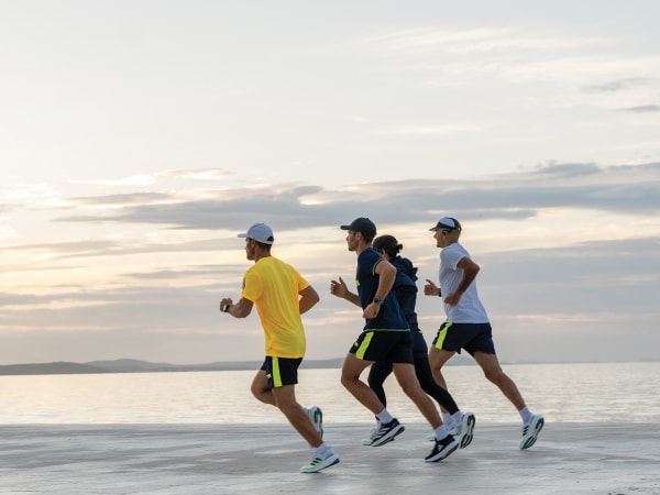 Fire deltakere løper sammen på stranden.