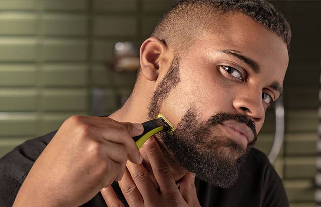 En mann barberer det korte skjegget sitt vertikalt fra kinnet til kjevelinjen, noe som resulterer i et glattbarbert område.  
