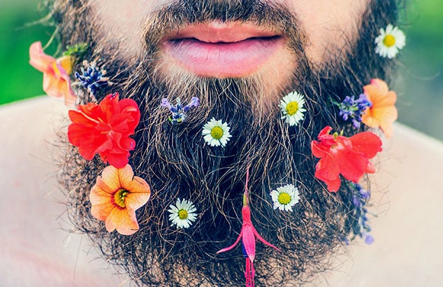 Nærbilde av et mannsskjegg med mange forskjellige og fargerike blomster i det.