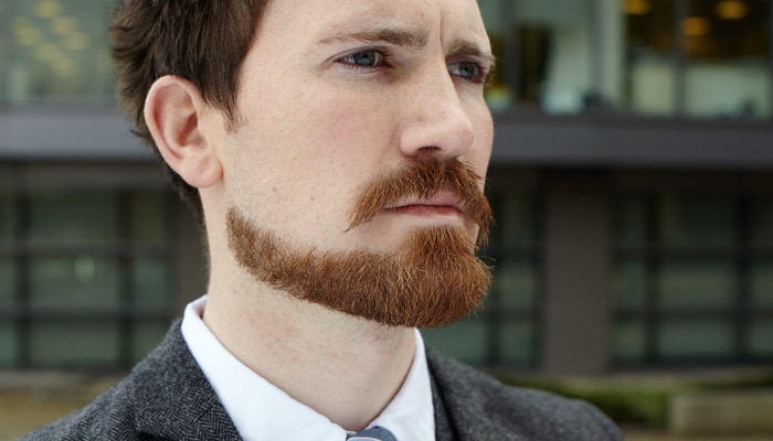 Rødhåret mann med formet bart og smalt skjegg fra kjevelinjen til litt bredere hvor det dekker haken.