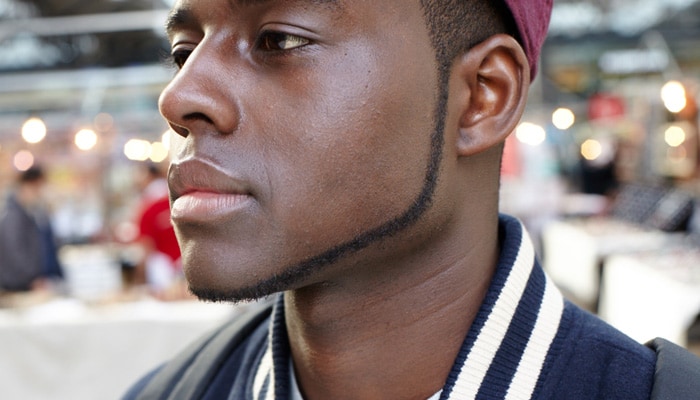 Mann i caps med 1 cm stripe med ansiktshår som går rundt kanten av ansiktet fra kjevelinje til kjevel-inje.